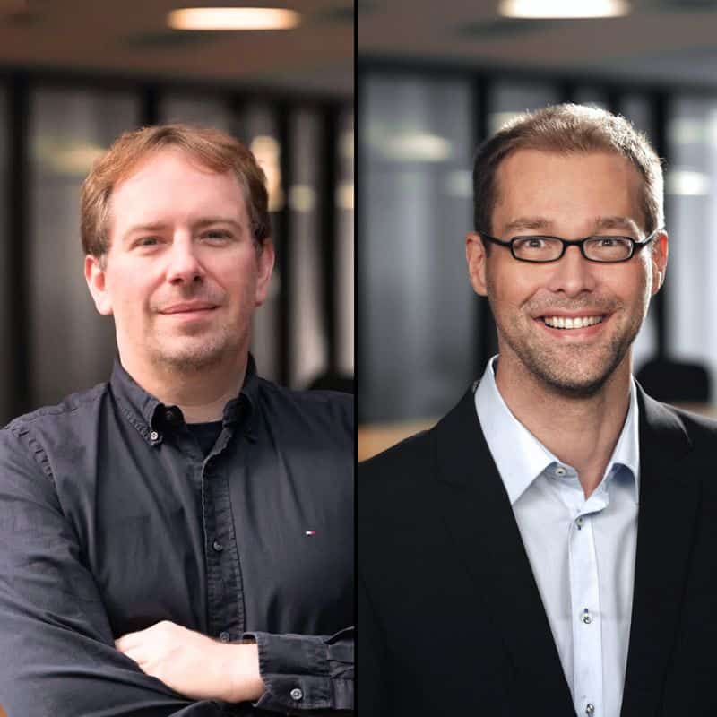 Zwei professionelle Männer in Business-Umfeld, symbolisieren Innovation und Kompetenz in der IT-Branche.